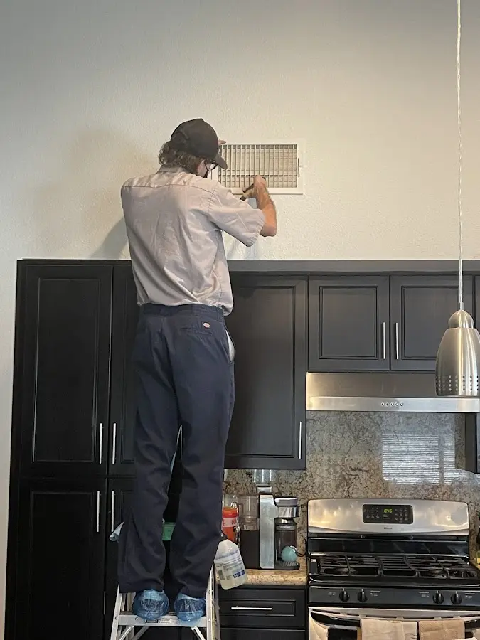 Technician inspecting an air vent during HVAC service in Clyde